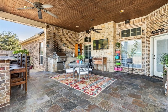 view of patio featuring outdoor dining space, an outdoor kitchen, a grill, and a ceiling fan