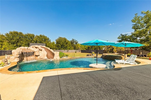 view of pool featuring a patio, a pool with connected hot tub, a water slide, and a fenced backyard