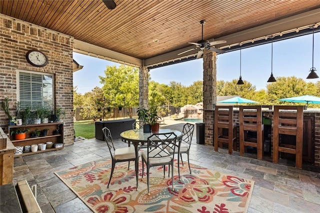 view of patio / terrace with outdoor dining space, fence, a fenced in pool, ceiling fan, and outdoor dry bar