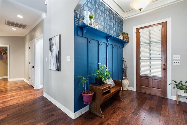 interior space with baseboards, wood finished floors, visible vents, and ornamental molding