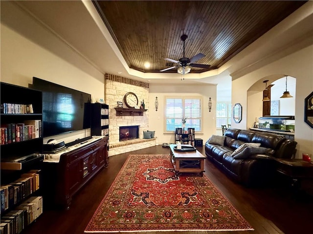 living room with a fireplace, a tray ceiling, ornamental molding, and wooden ceiling