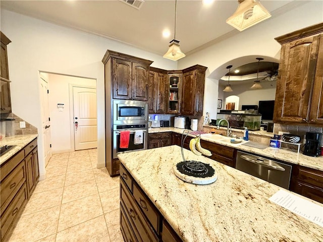 kitchen featuring light tile patterned flooring, dark brown cabinetry, sink, decorative light fixtures, and stainless steel appliances