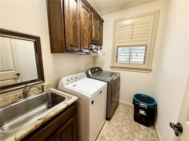 clothes washing area with cabinets, crown molding, sink, and independent washer and dryer