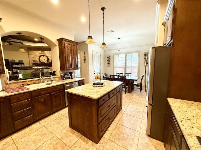 kitchen with light tile patterned floors, crown molding, appliances with stainless steel finishes, hanging light fixtures, and a kitchen island