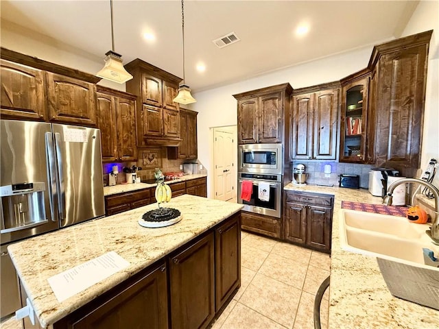 kitchen with sink, stainless steel appliances, dark brown cabinetry, decorative backsplash, and decorative light fixtures