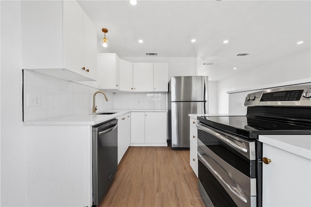 kitchen with sink, appliances with stainless steel finishes, white cabinetry, decorative backsplash, and decorative light fixtures