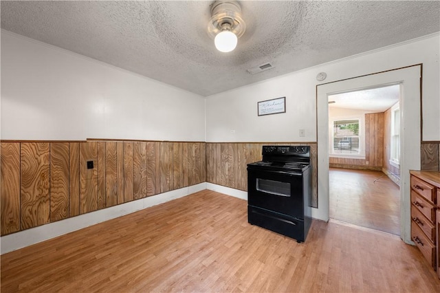 kitchen featuring wood walls, black electric range, a textured ceiling, and light hardwood / wood-style flooring