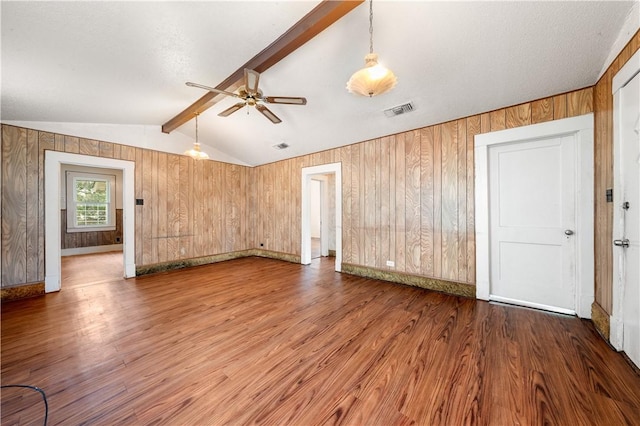 interior space with wood walls, ceiling fan, lofted ceiling with beams, and hardwood / wood-style flooring