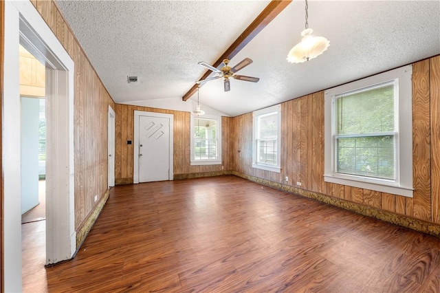 spare room with dark hardwood / wood-style floors, lofted ceiling with beams, a textured ceiling, and wooden walls