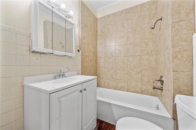 full bathroom featuring ornamental molding, vanity, tile walls, toilet, and tiled shower / bath