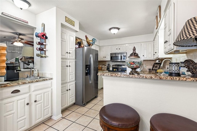 kitchen with white cabinetry, sink, backsplash, light tile patterned floors, and appliances with stainless steel finishes