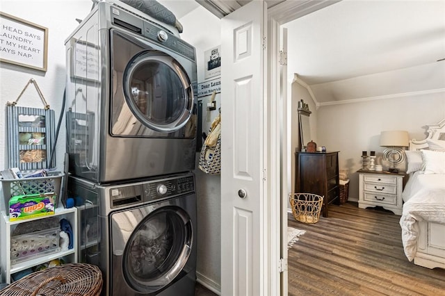 laundry room with dark hardwood / wood-style flooring, stacked washing maching and dryer, and ornamental molding