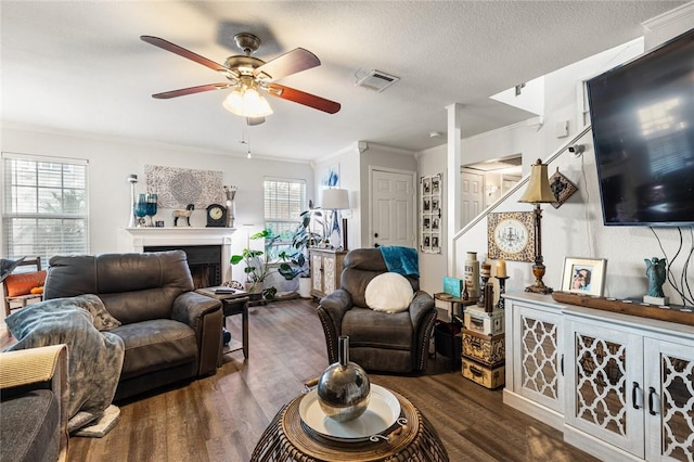 living room with a textured ceiling, ceiling fan, dark hardwood / wood-style floors, and ornamental molding