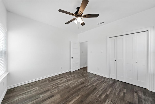 unfurnished bedroom featuring a ceiling fan, dark wood-style floors, visible vents, baseboards, and a closet