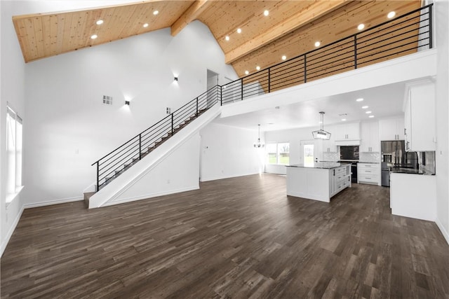 unfurnished living room featuring beamed ceiling, wooden ceiling, stairs, and dark wood-style flooring