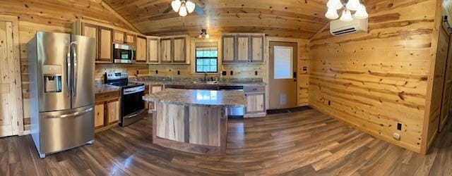 kitchen with wood walls, a kitchen island, appliances with stainless steel finishes, and vaulted ceiling