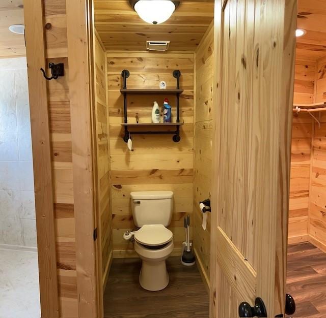 bathroom with wooden ceiling, hardwood / wood-style flooring, toilet, and wooden walls