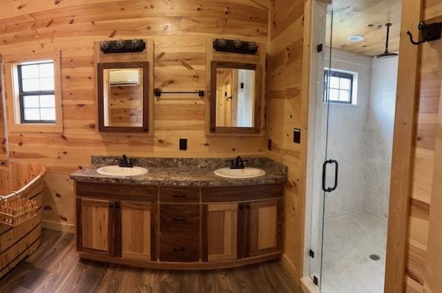 bathroom with vanity, wooden walls, hardwood / wood-style flooring, and a shower with shower door