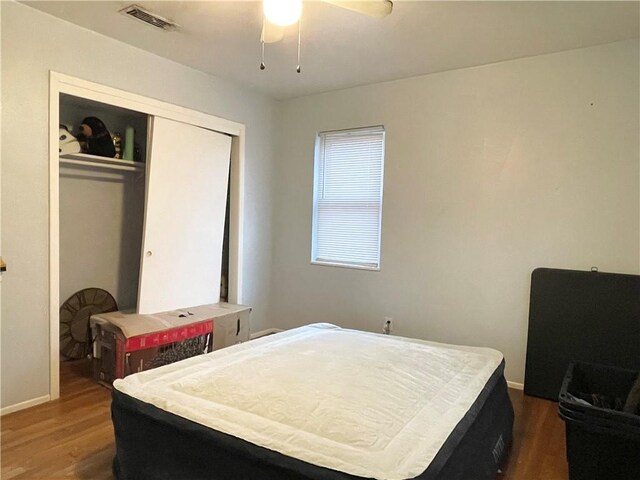 bedroom with dark wood-type flooring, ceiling fan, and a closet