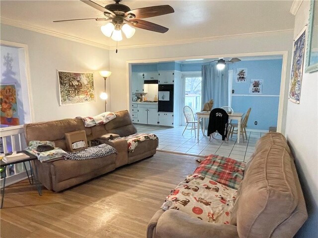 living room with ornamental molding, ceiling fan, and light wood-type flooring