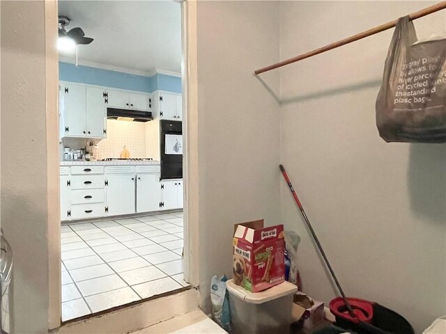 interior space featuring light tile patterned floors, crown molding, ceiling fan, tasteful backsplash, and white cabinets