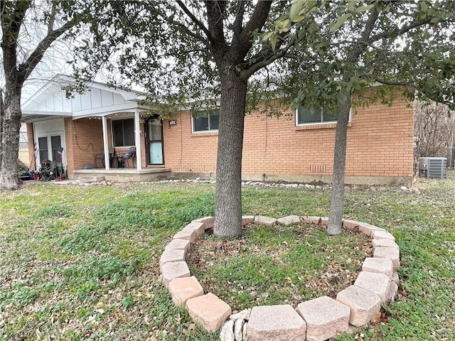 exterior space with central AC unit and a lawn