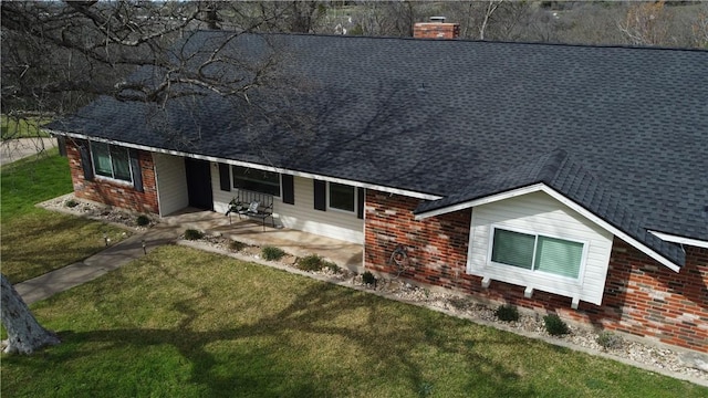 exterior space with a yard, brick siding, and a shingled roof