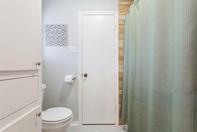 bathroom with a shower with curtain, tile patterned floors, and toilet