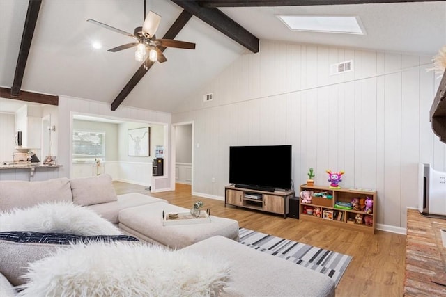 living area with visible vents, lofted ceiling with beams, and wood finished floors