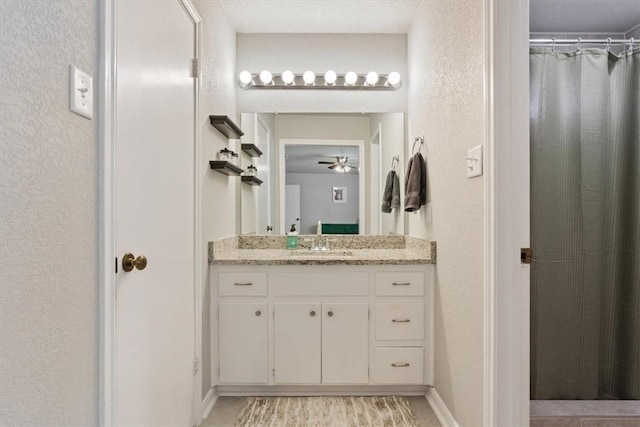 full bath with a shower with shower curtain, a textured wall, wood finished floors, vanity, and a ceiling fan