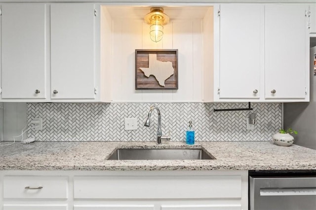 kitchen featuring dishwasher, white cabinets, tasteful backsplash, and a sink