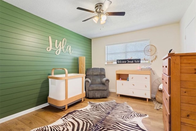 bedroom with baseboards, a textured ceiling, ceiling fan, and wood finished floors