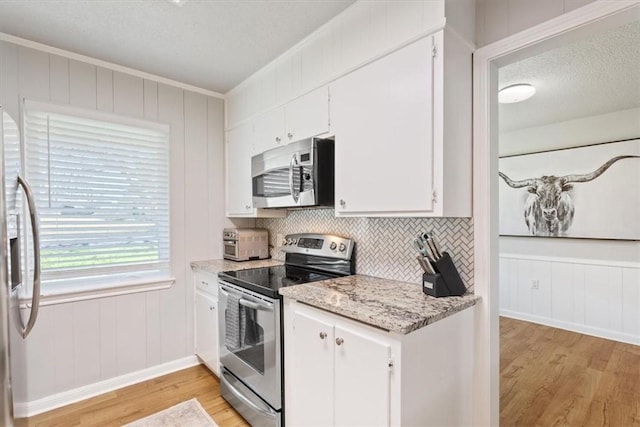 kitchen featuring light wood-type flooring, a textured ceiling, appliances with stainless steel finishes, and white cabinets