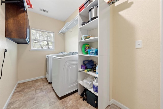 clothes washing area featuring washing machine and dryer and cabinets