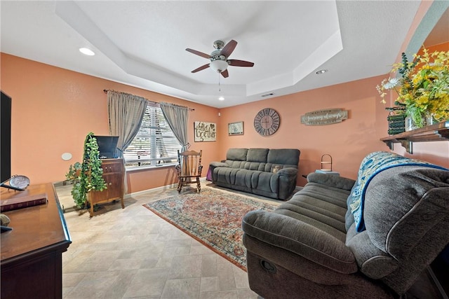 living room featuring ceiling fan and a tray ceiling