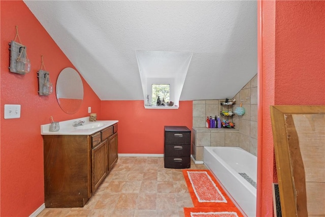 bathroom with vanity, a textured ceiling, vaulted ceiling, and a bathing tub