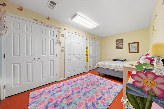 bedroom featuring concrete flooring and multiple closets