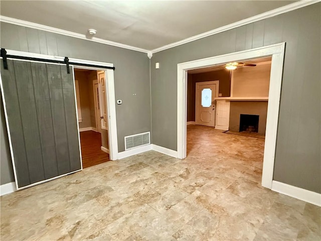 unfurnished room featuring ornamental molding, a barn door, and ceiling fan