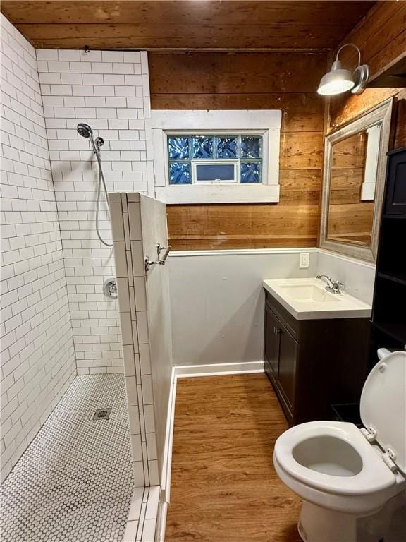 bathroom featuring wood ceiling, a tile shower, vanity, wooden walls, and hardwood / wood-style flooring