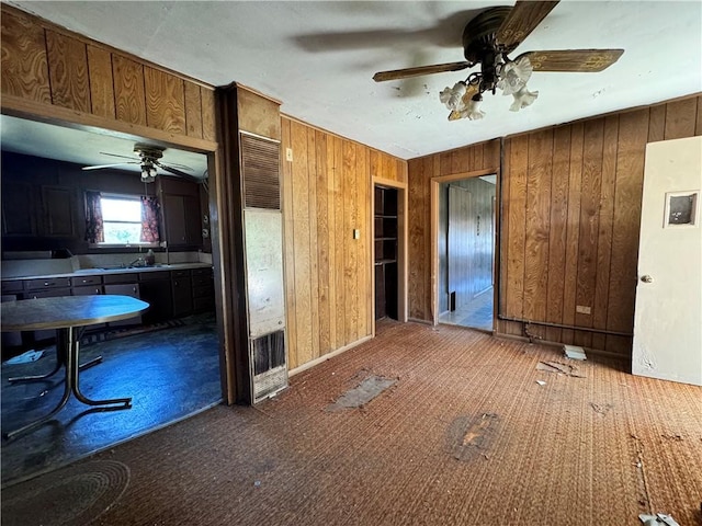 interior space with wood walls, sink, and ceiling fan