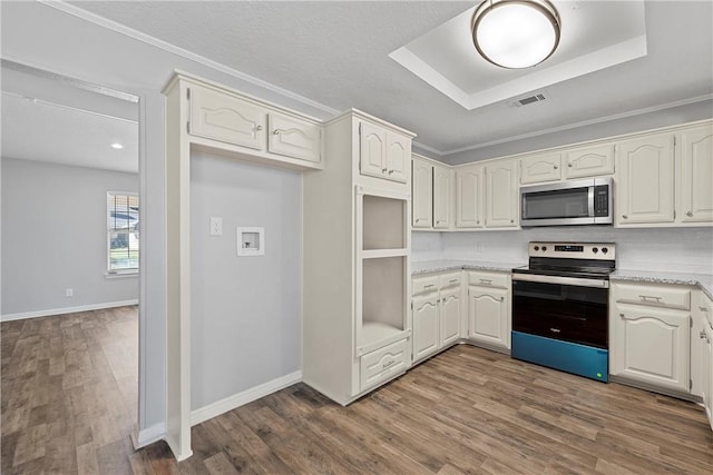 kitchen with dark wood-type flooring, white cabinets, a raised ceiling, decorative backsplash, and stainless steel appliances