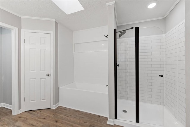 bathroom featuring hardwood / wood-style floors, a skylight, separate shower and tub, ornamental molding, and a textured ceiling