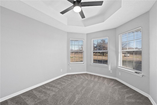 carpeted empty room with a tray ceiling and ceiling fan