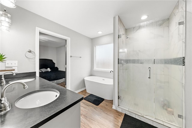 bathroom with plus walk in shower, vanity, and hardwood / wood-style floors