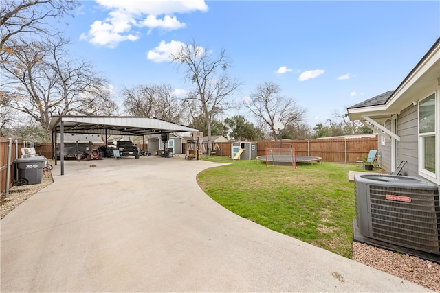 view of yard featuring a trampoline, central air condition unit, a storage shed, and a carport