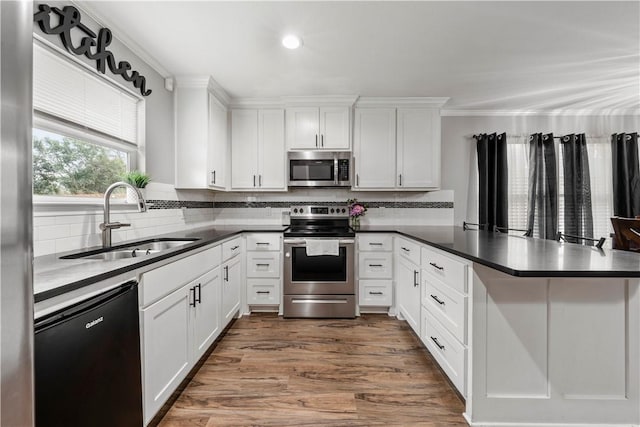 kitchen featuring appliances with stainless steel finishes, white cabinets, decorative backsplash, sink, and kitchen peninsula