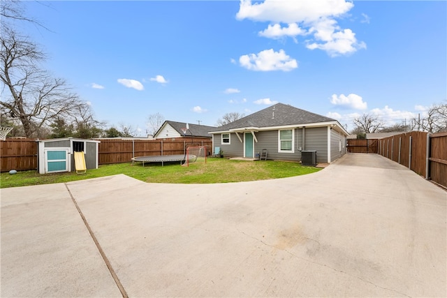 back of house featuring a storage unit, a yard, and central AC