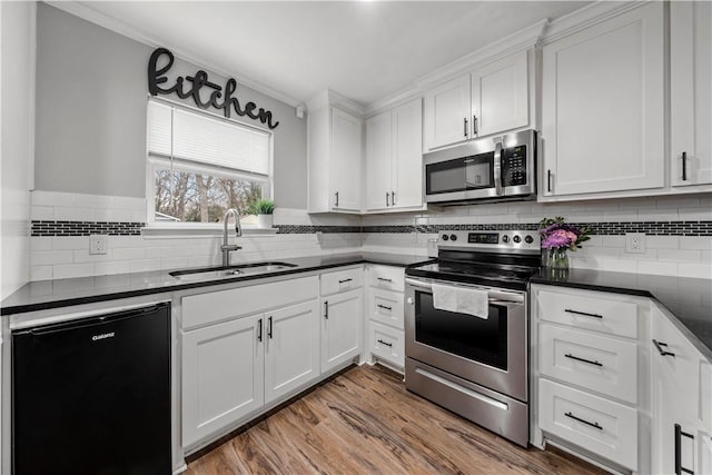 kitchen with white cabinetry, hardwood / wood-style flooring, sink, backsplash, and appliances with stainless steel finishes