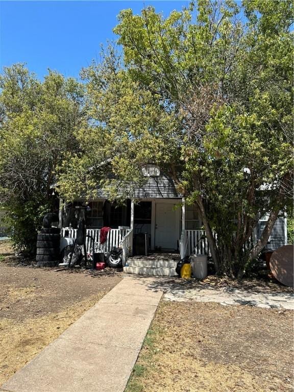 view of property hidden behind natural elements featuring covered porch