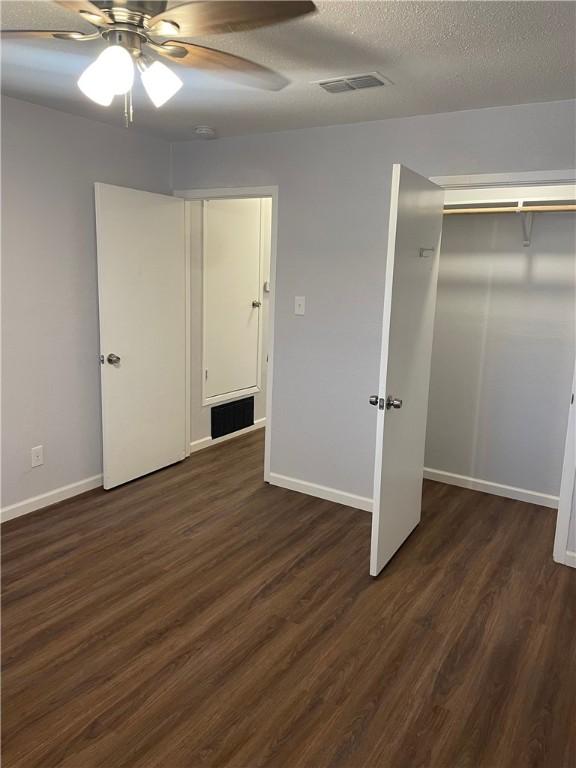 unfurnished bedroom featuring ceiling fan, a closet, dark wood-type flooring, and a textured ceiling